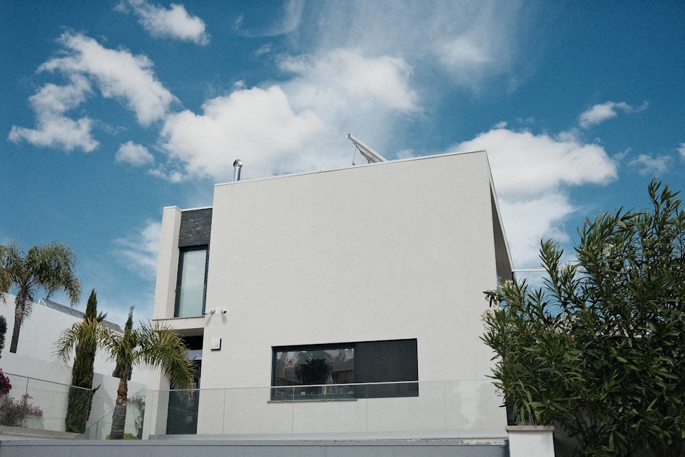 Fachada de casa branca com janela horizontal de alumínio preto e guarda-corpo de vidro